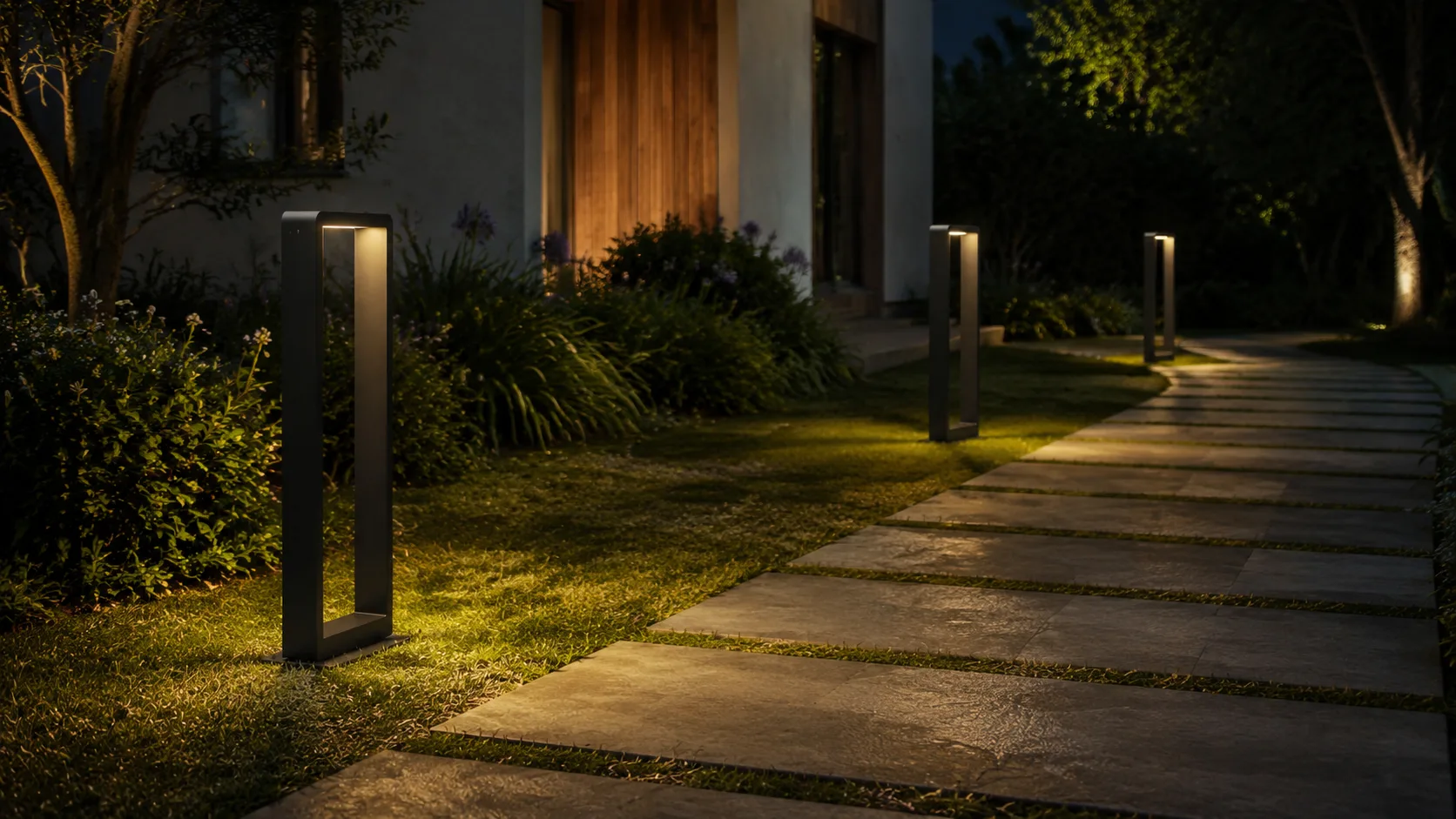 Balizas negras iluminando un sendero de piedra en un jardín de noche